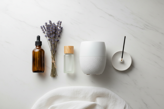 Aromatherapy starter kit flat lay on white marble with essential oil bottle, ceramic diffuser, carrier oil, lavender and incense stick holder
