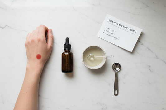 Essential oil safety essentials including a dark glass bottle, carrier oil, dropper and measuring spoon on a white marble surface