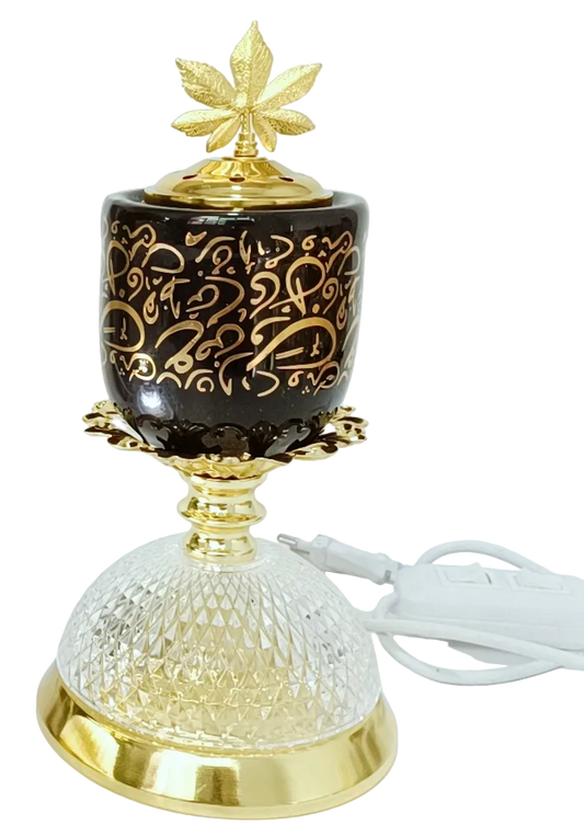 Decorative lamp and burner on black background, gold accents, and leaf design on the lid, an LED lamp below.