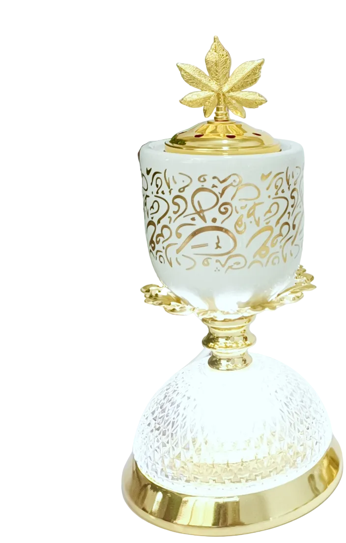 Decorative white and gold burner and lamp with intricate designs on a surface with a framed picture in the background.